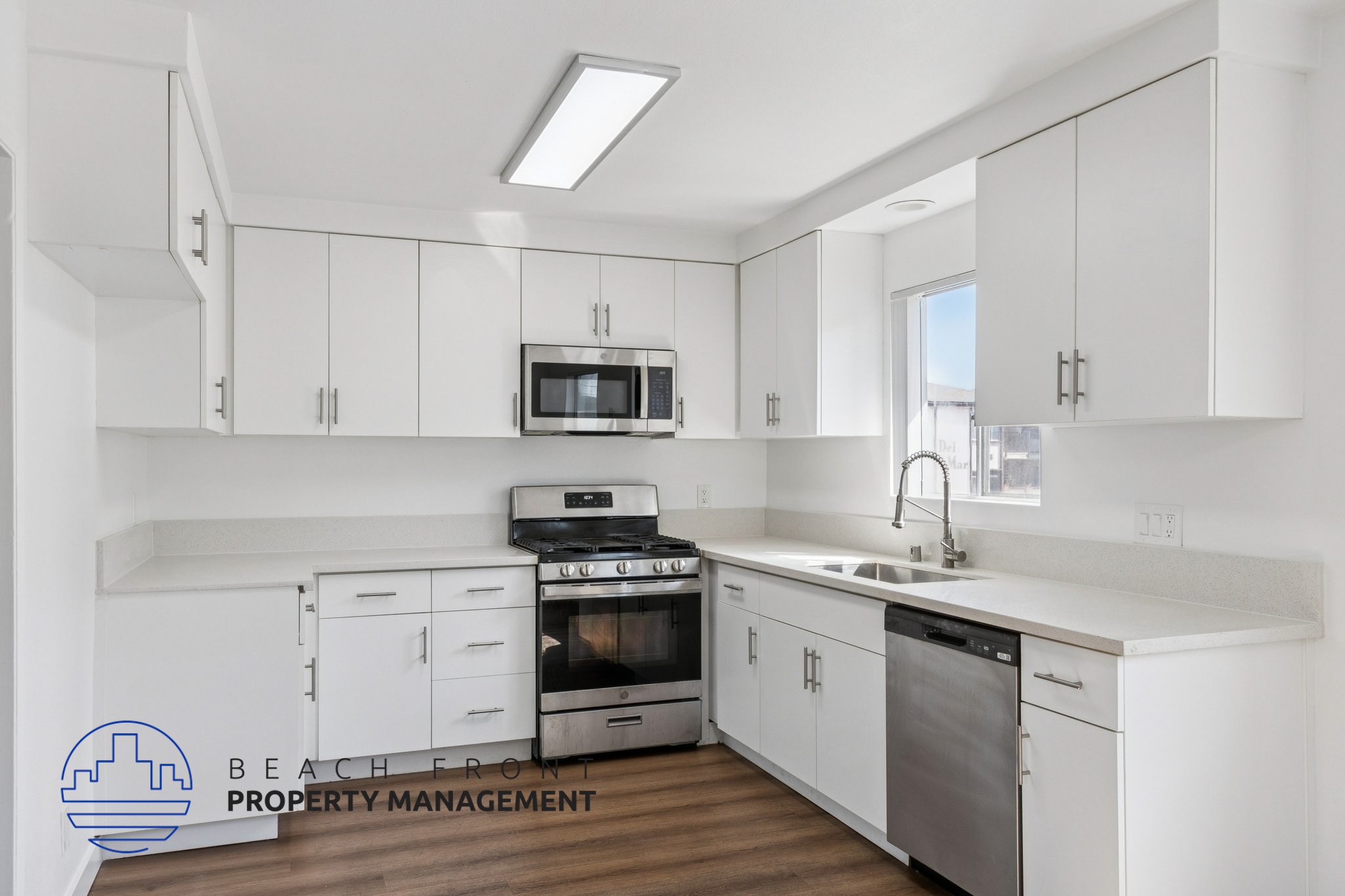 A modern kitchen with white cabinets and stainless steel appliances.